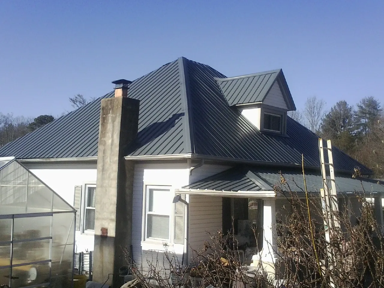 Dark blue standing seam metal roof on a white farmhouse with dormer — Slate & Tile Roof Repair by Roofing Brothers in Lava Hot Springs