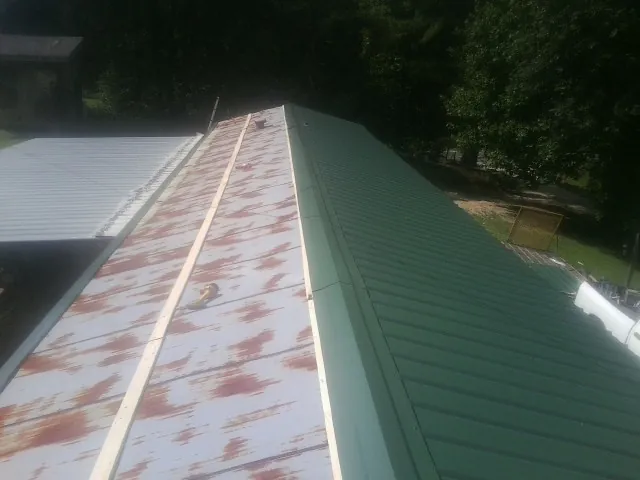 Old rusted panels beside newly installed green metal roofing — Wind Damage Roof Repair by Roofing Brothers in Lava Hot Springs