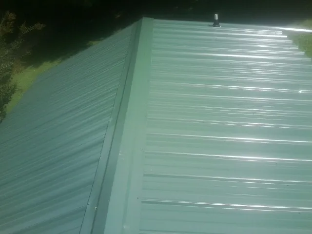 New green metal panels meeting at the ridge of a roof — Flat Roof Repair work by our crew in Lava Hot Springs