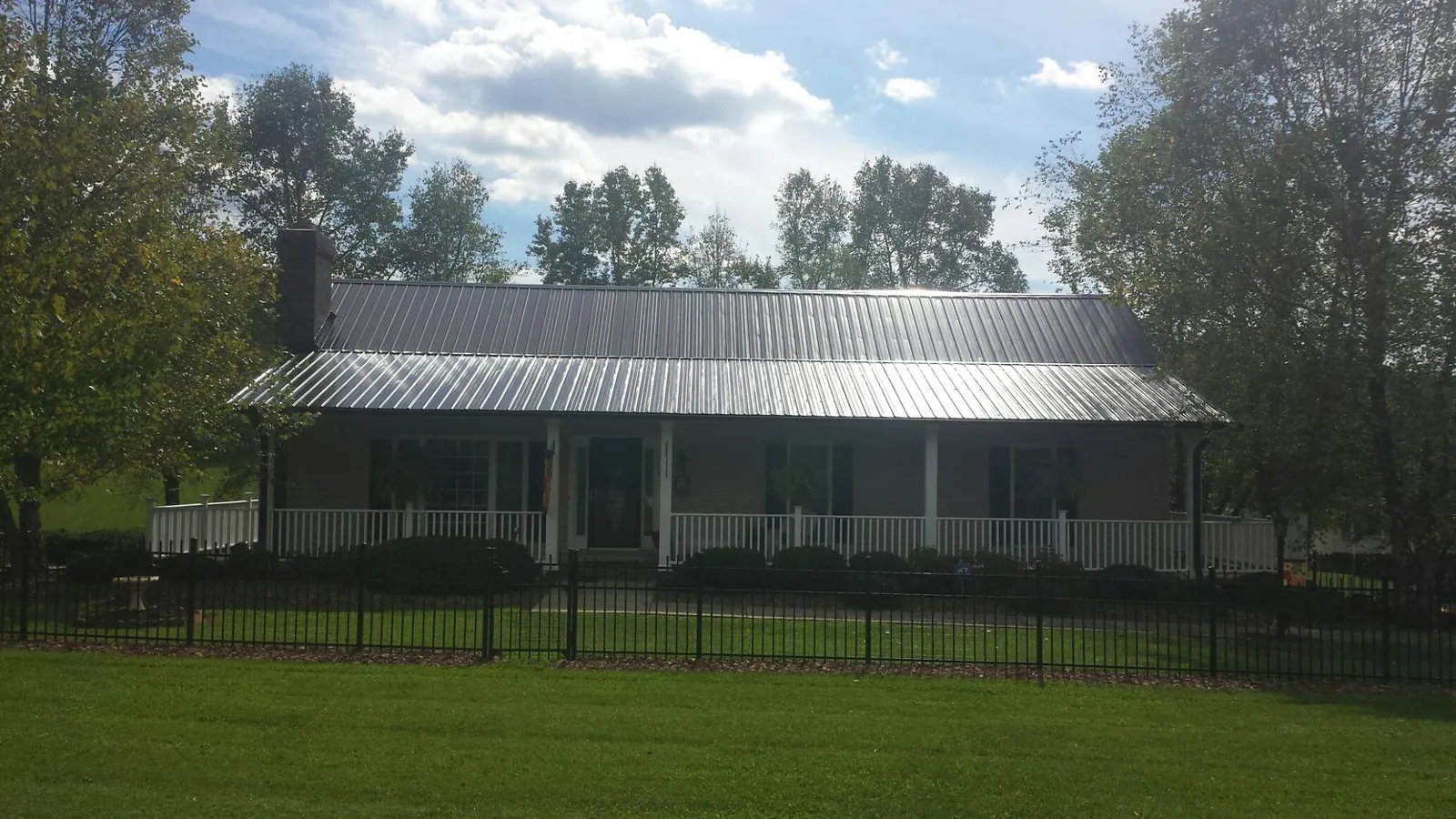 Gray metal roof on a brick ranch with a full width front porch — Gutter Guard Installation work by our crew in Lava Hot Springs