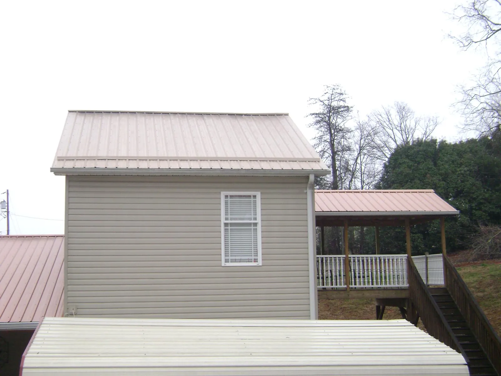 Tan metal roofs on a two story addition and attached porch, from a Roof Replacement job in Lava Hot Springs